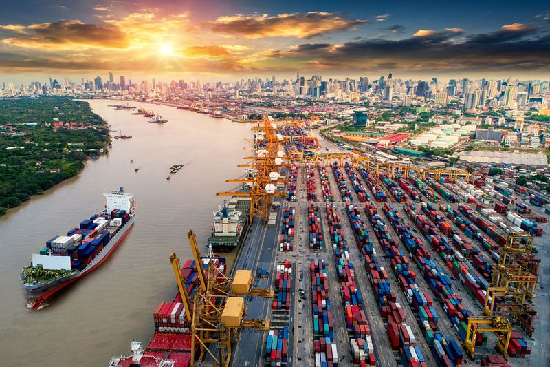 Container Cargo Ship and Cargo Plane With Working Crane Bridge in Shipyard at Sunrise