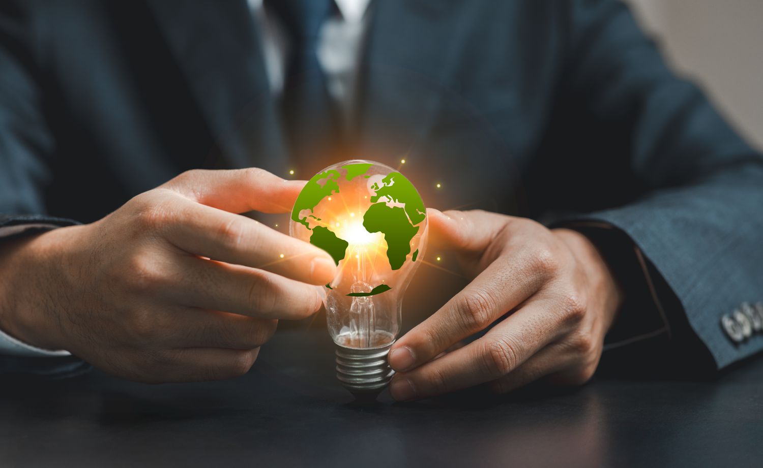 A businessperson holds a light bulb featuring a green Earth to represent sustainability and environmental responsibility in the modern world.