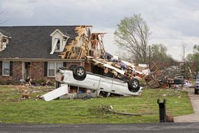 A home damaged by a tornado and an upside down truck in a yard.