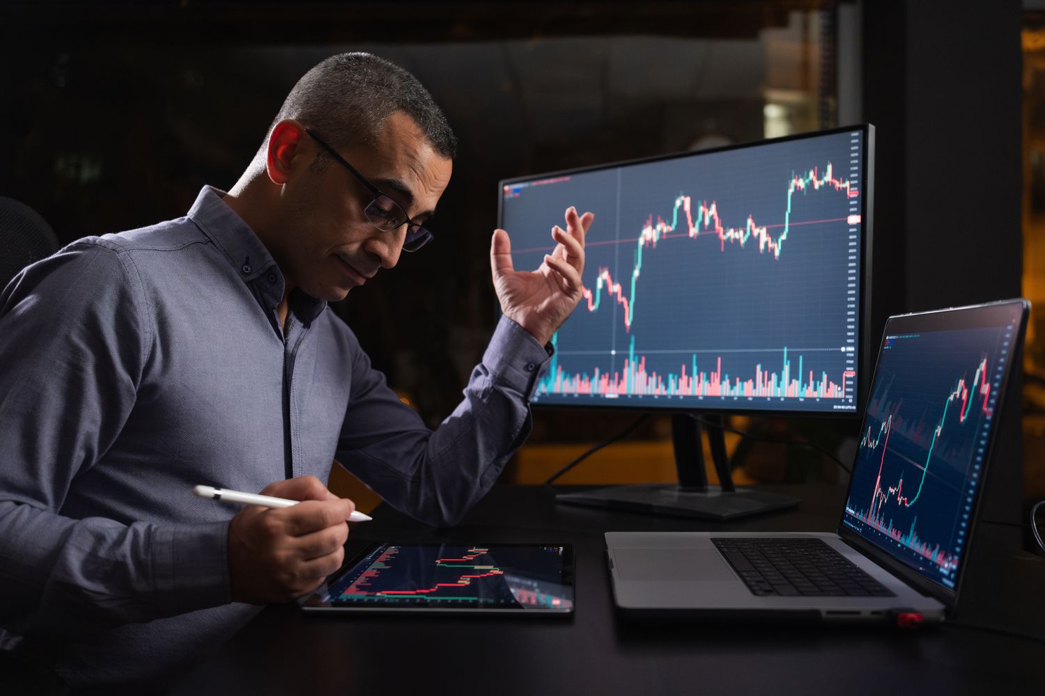 An investor researches possible stocks to buy using multiple internet-connected devices.