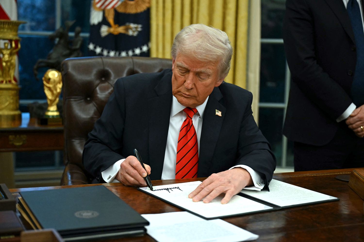 President Donald Trump signs an executive order in the Oval Office of the White House on Feb. 10, 2025, in Washington, DC