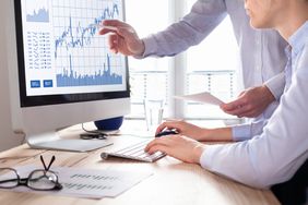 Team of traders working with forex (foreign exchange) trading charts and graphs on computer screen.