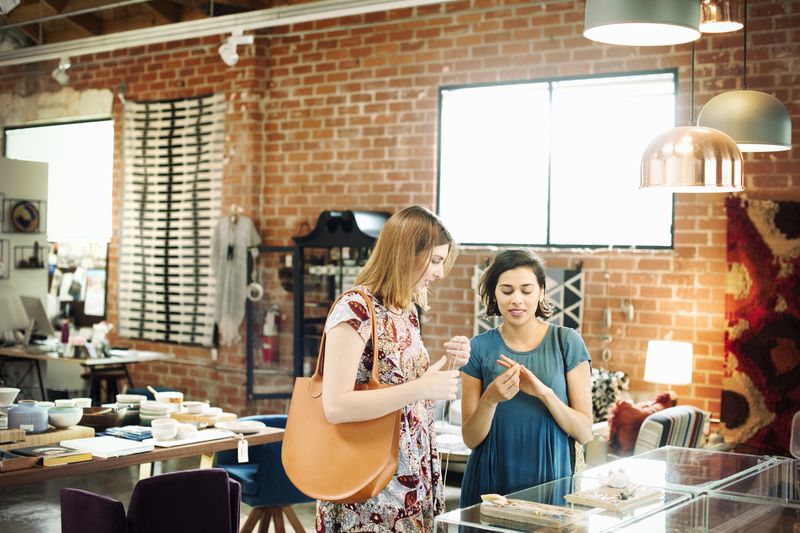 Two women shop at a small store trying on jewelry