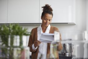 A woman stands in her kitchen reading a statement