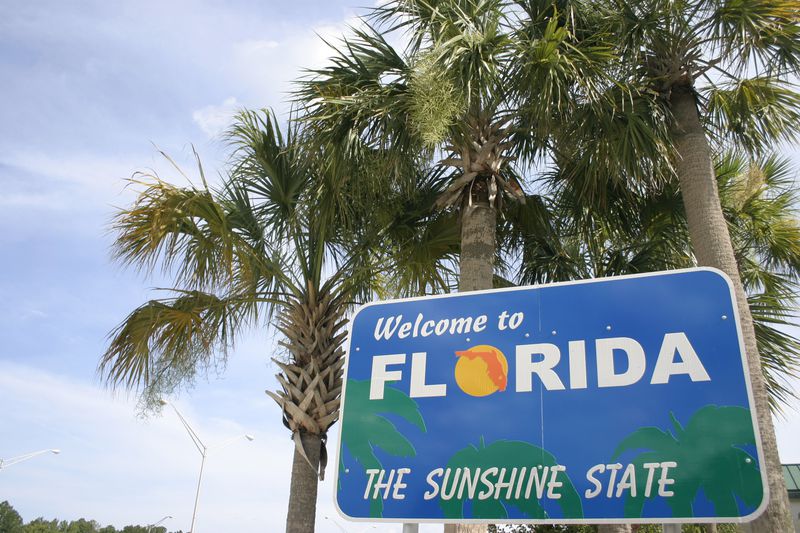 A tropical scene and sign welcoming you to the state of Florida.