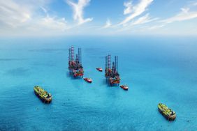 Aerial view of two oil rigs in the ocean surrounded by ships