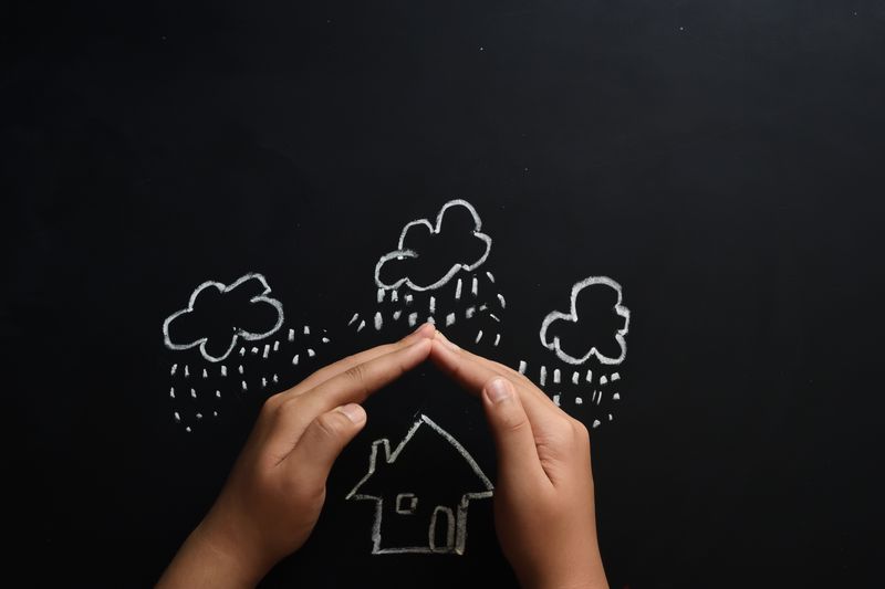Home Insurance Concept Child Protecting House by Hands with Copy Space