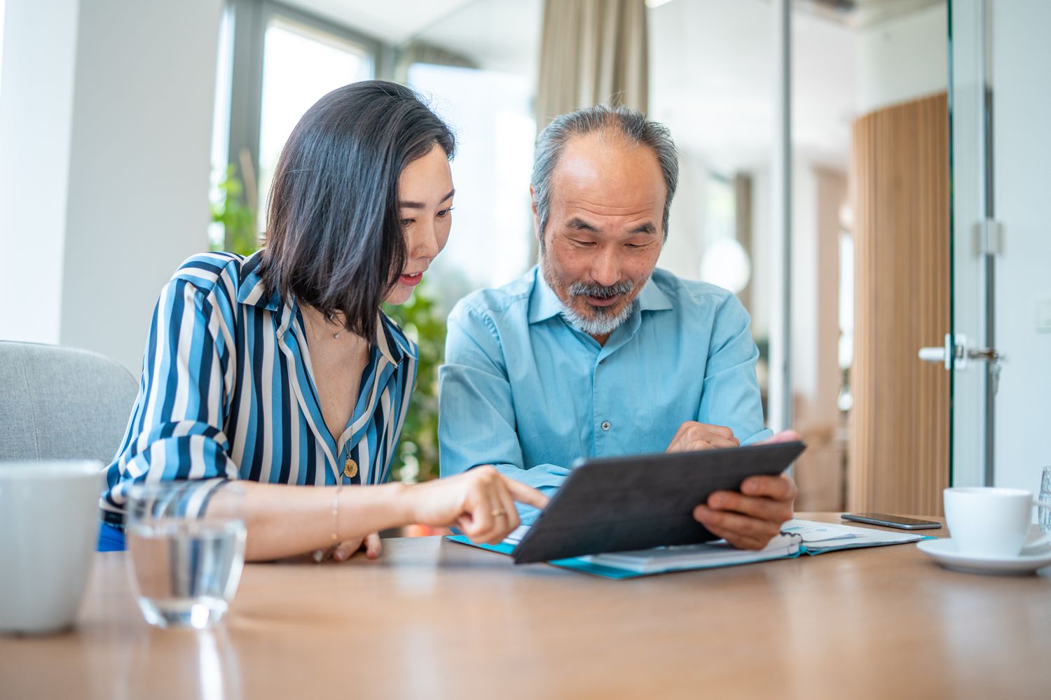 Older couple sitting at their dining room table and looking together at mortgage rates on a tablet