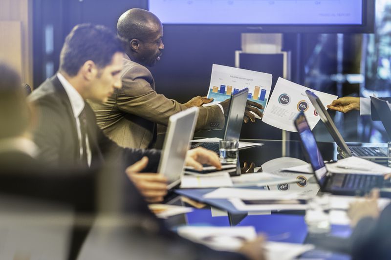 Investment professionals working at a desk with laptops and portfolio documents