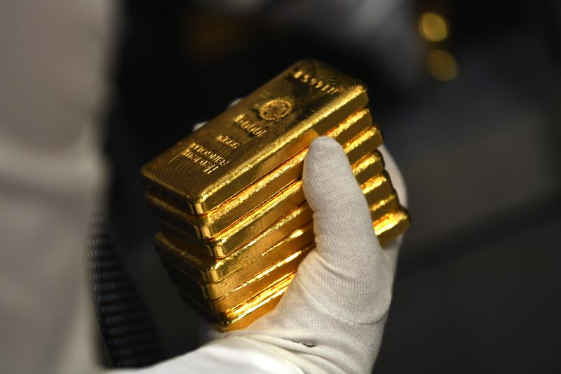 Gloved hand holding several bars of gold.