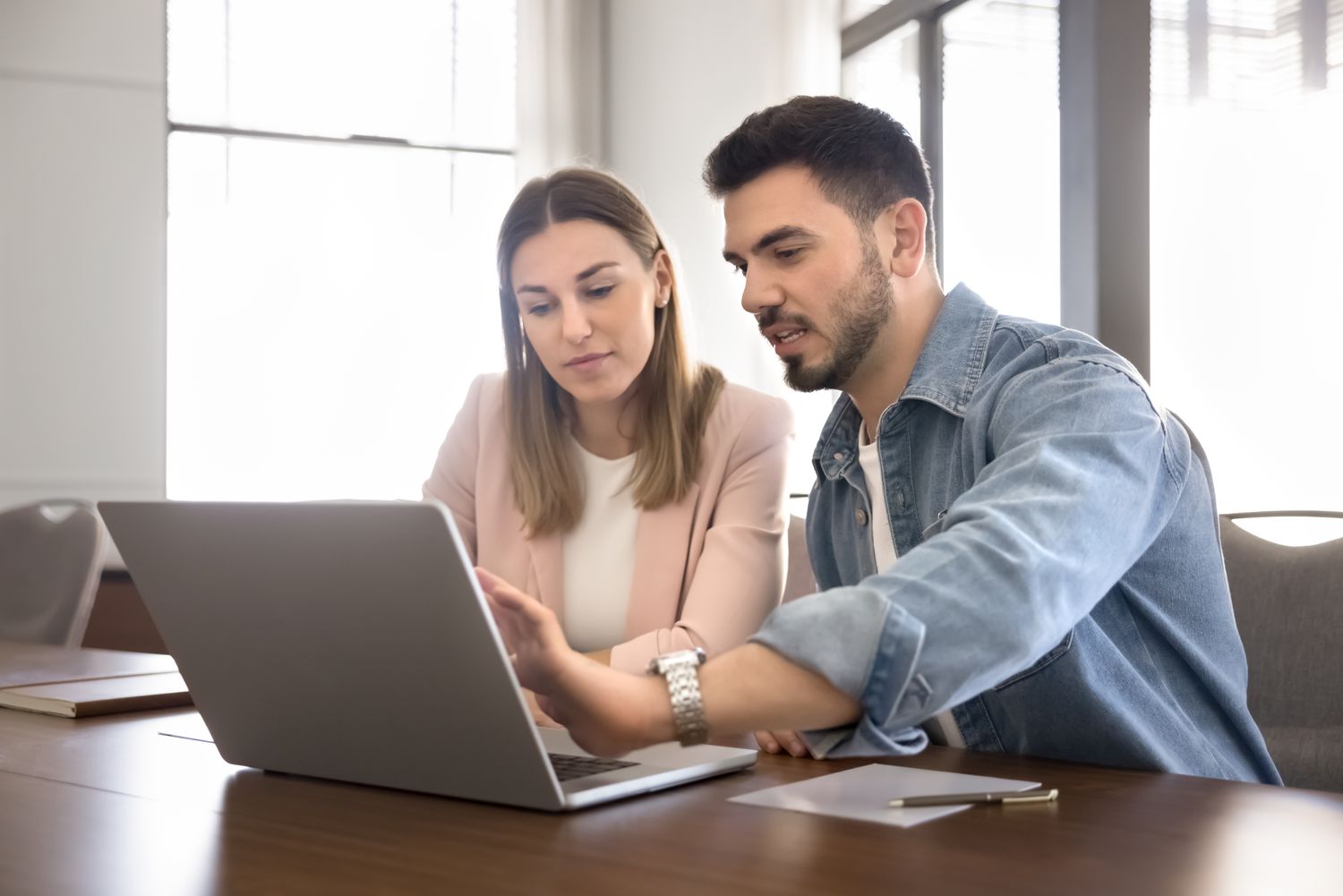 Young couple sitting at a table and looking together a mortgage rates on a laptop