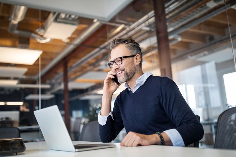 man on phone in front of laptop in an office