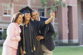 Female African American college graduate taking photo with parents 