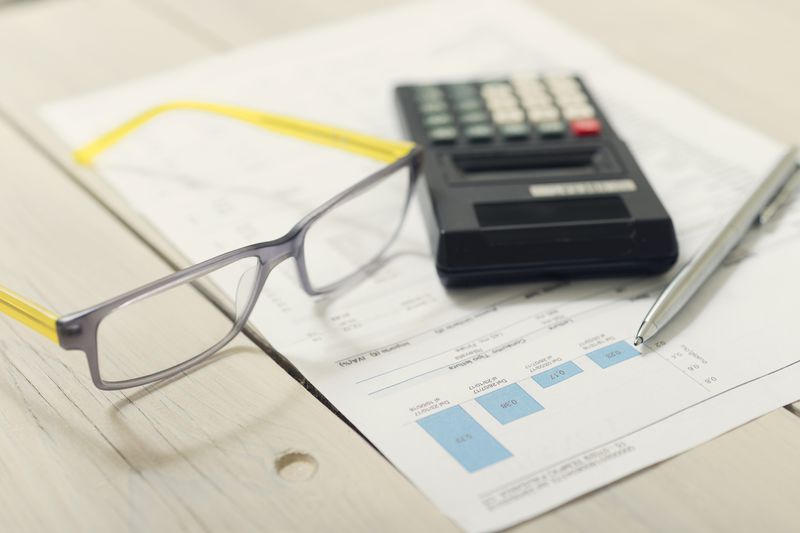 A calculator and tax forms on a wooden table