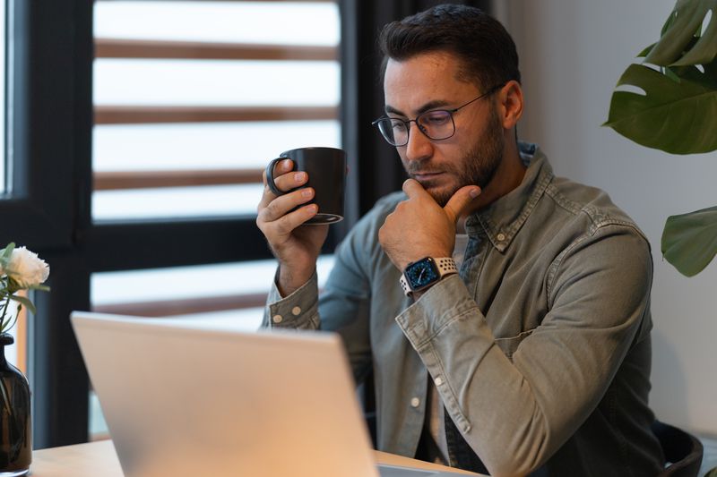 Man in his 30s sitting at home and looking seriously at his laptop
