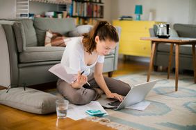 Woman sits on floor with computer.