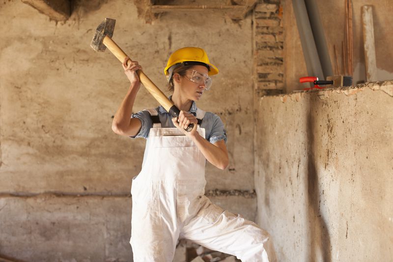 a female construction worker swinging a sledgehammer