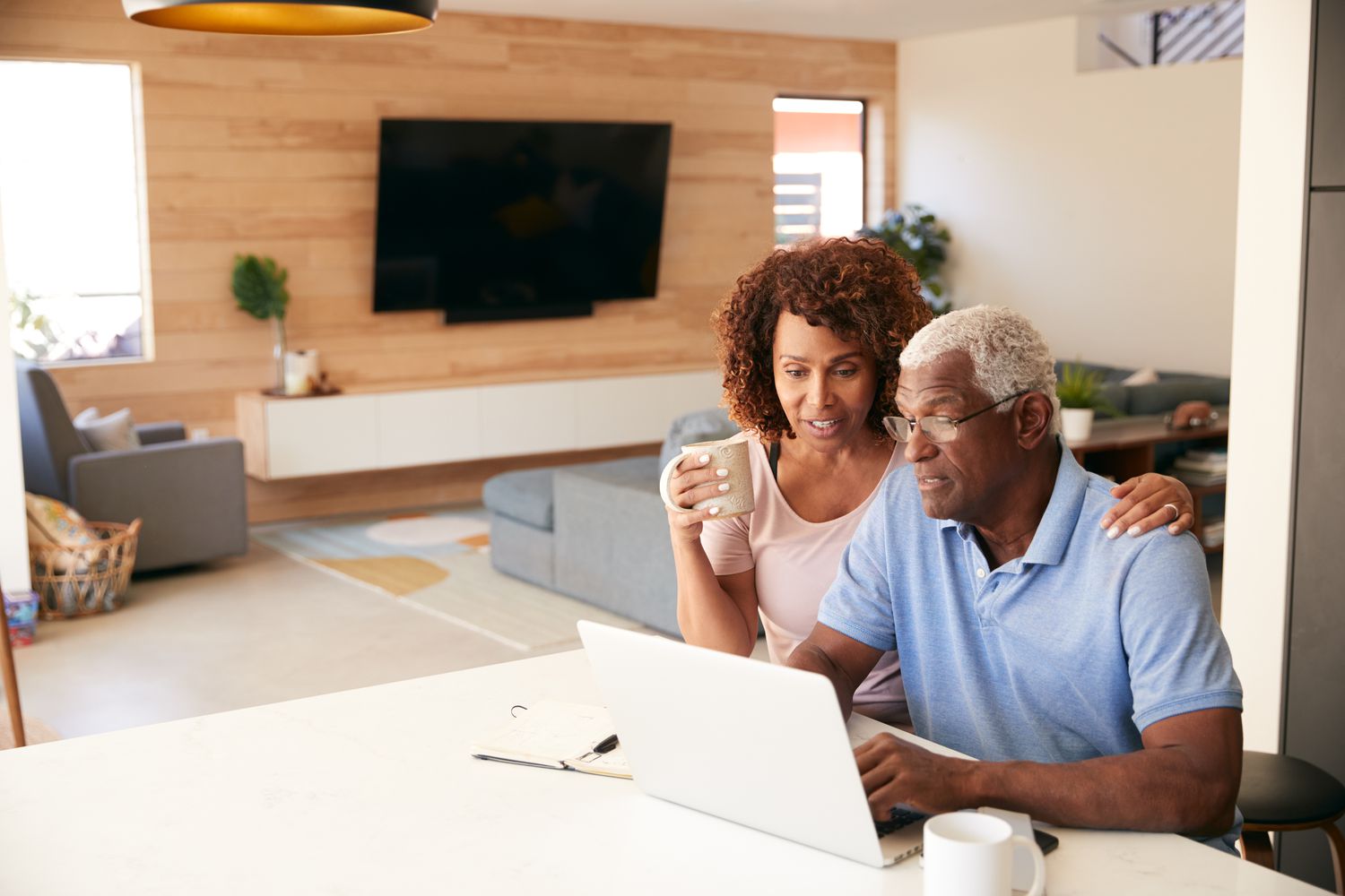 Older couple sitting at their dining room table and looking at mortgage rates on a laptop