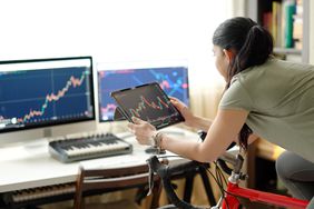 Woman on a stationary bike looking at charts on several screens.