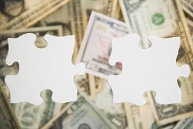 Puzzle pieces over a pile of money