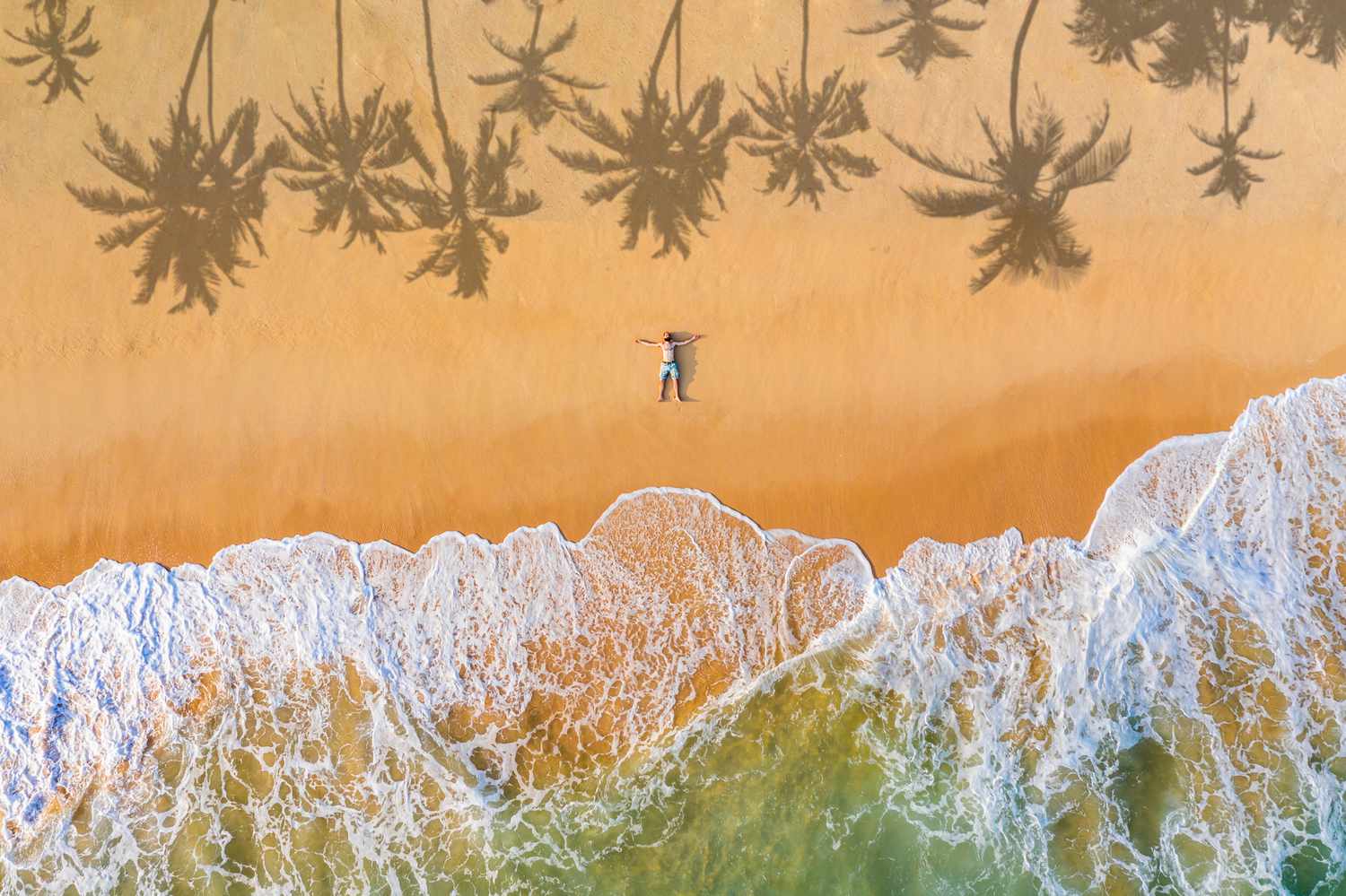 A guy lies on a sandy beach on a tropical island.