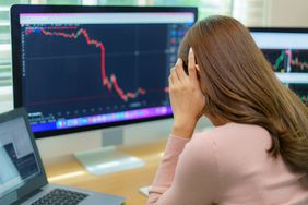 Woman holding her head looking at declining price on a chart