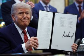 President Donald Trump holds up a signed executive order