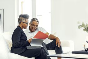 Two people seated on a couch, looking at folders