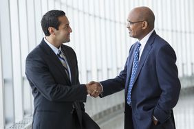 Two men shaking hands in a hallway of an office building