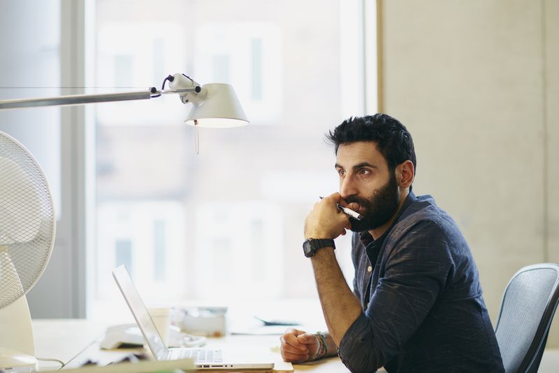 A person at a desk, thinking about retirement savings