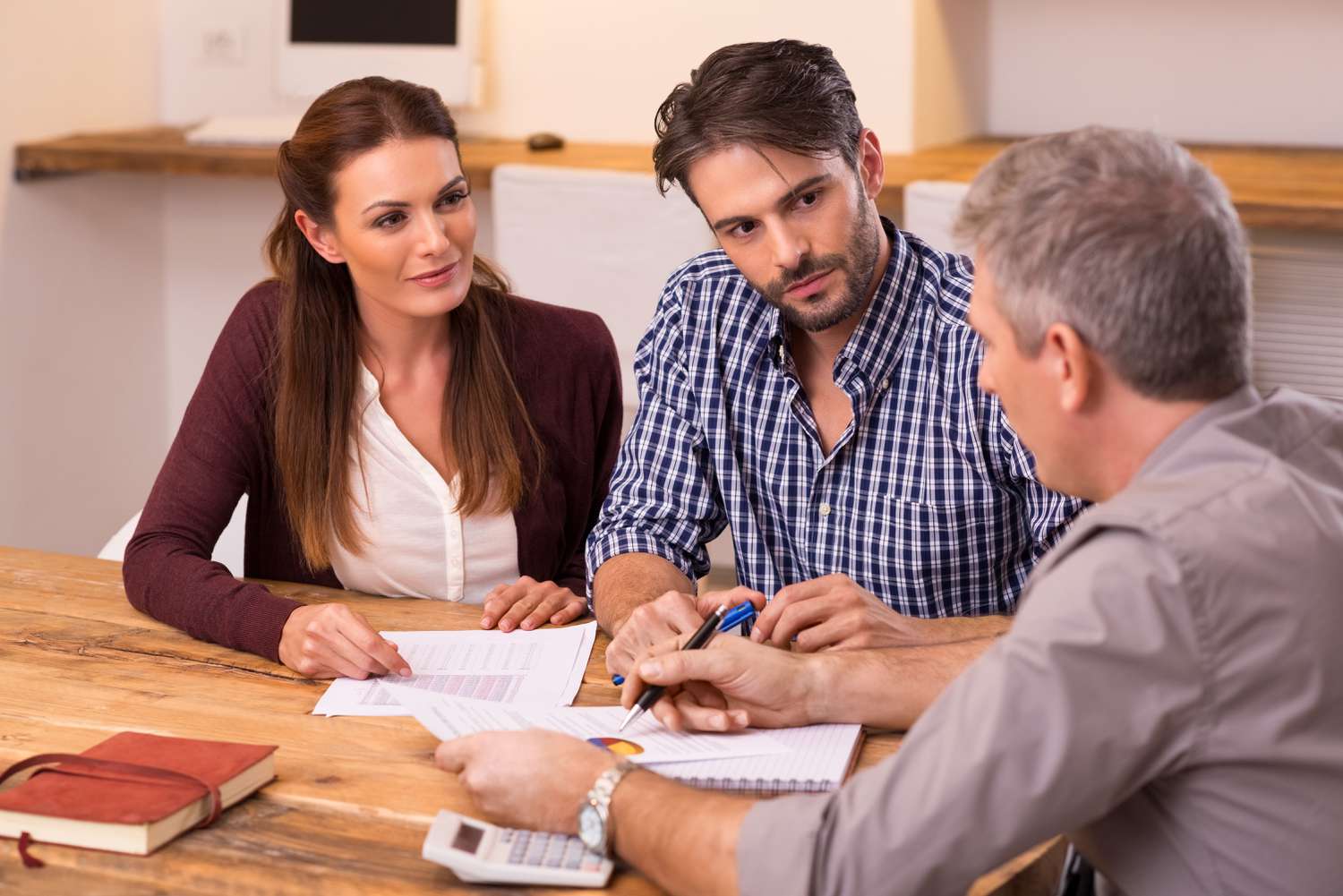 A couple meets with a financial advisor; they're sitting at a table and looking at documents.