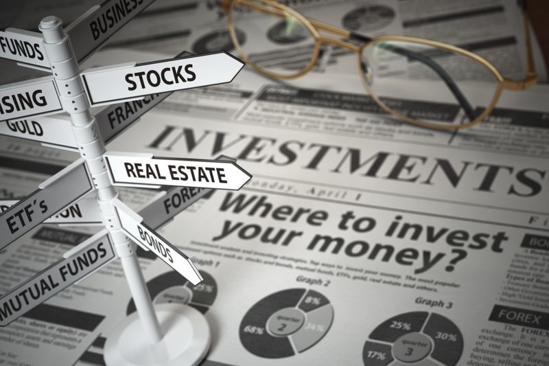 Road signs for different investments over a newspaper