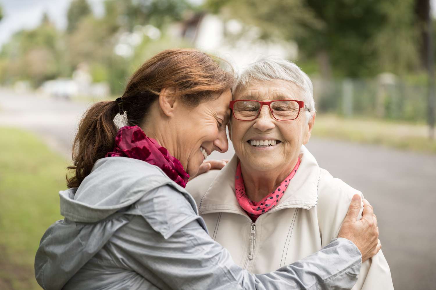 Happy senior woman and caregiver walking outdoors.