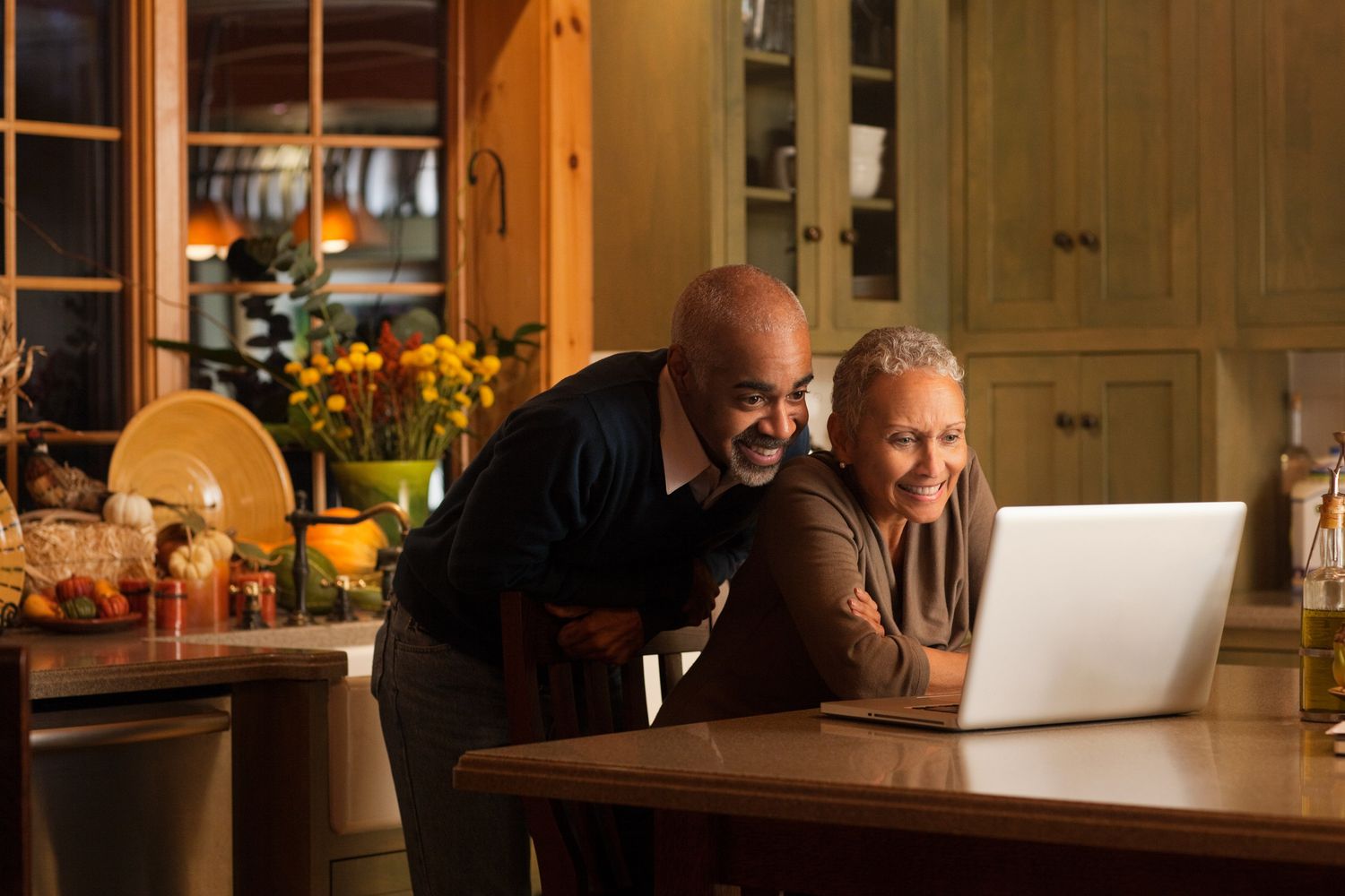 Mature couple looking at laptop together in their kitchen.