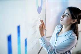 A person digital pen in hand pointing at financial analysis on a wall-sized screen.