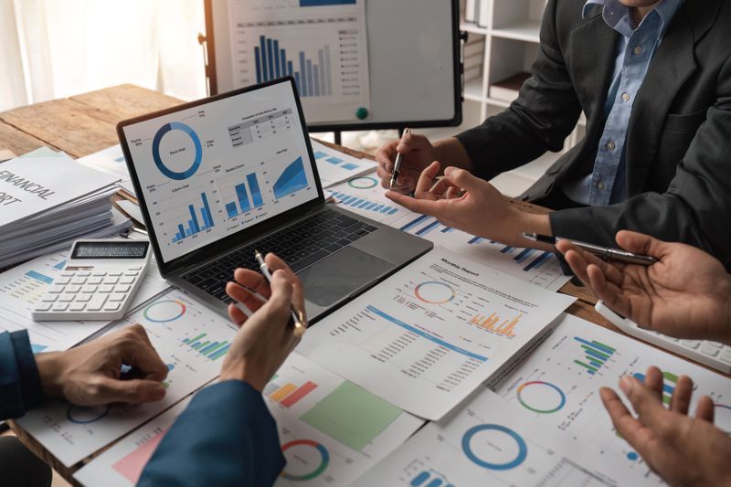 A group of financial analysts meet around a table cluttered with financial documents to discuss the merits of various exchange-listed securities that they can’t trade on a centralized exchange.