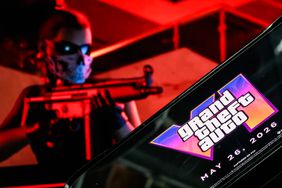 A phone displays the logo for "Grand Theft Auto VI" in front of a screen showing a trailer for the game. 