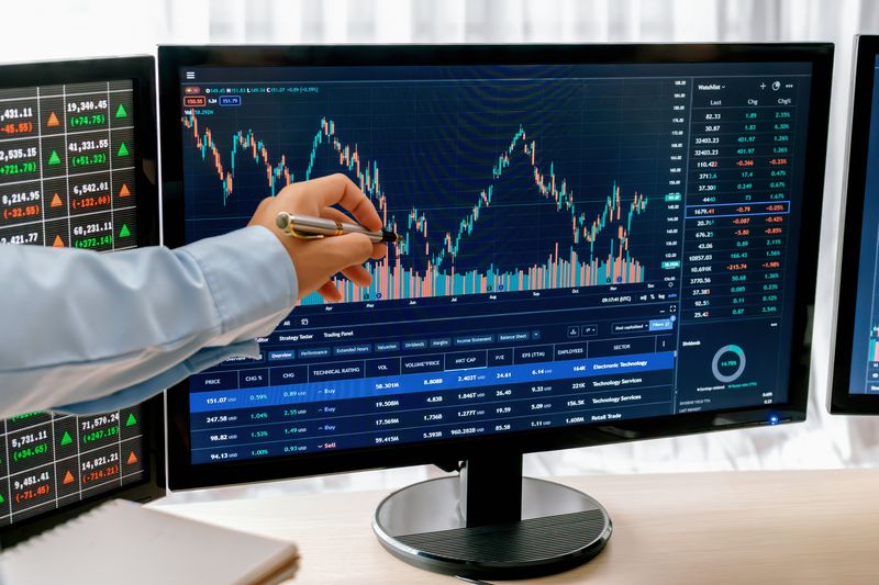 A trade manager points out a symmetrical distribution pattern on a computer monitor as they train a junior trader.