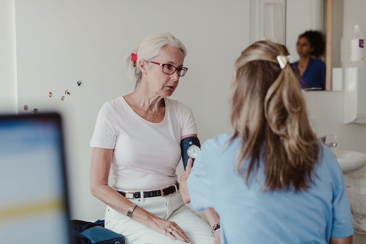 Older woman getting her blood pressure checked by a health care worker