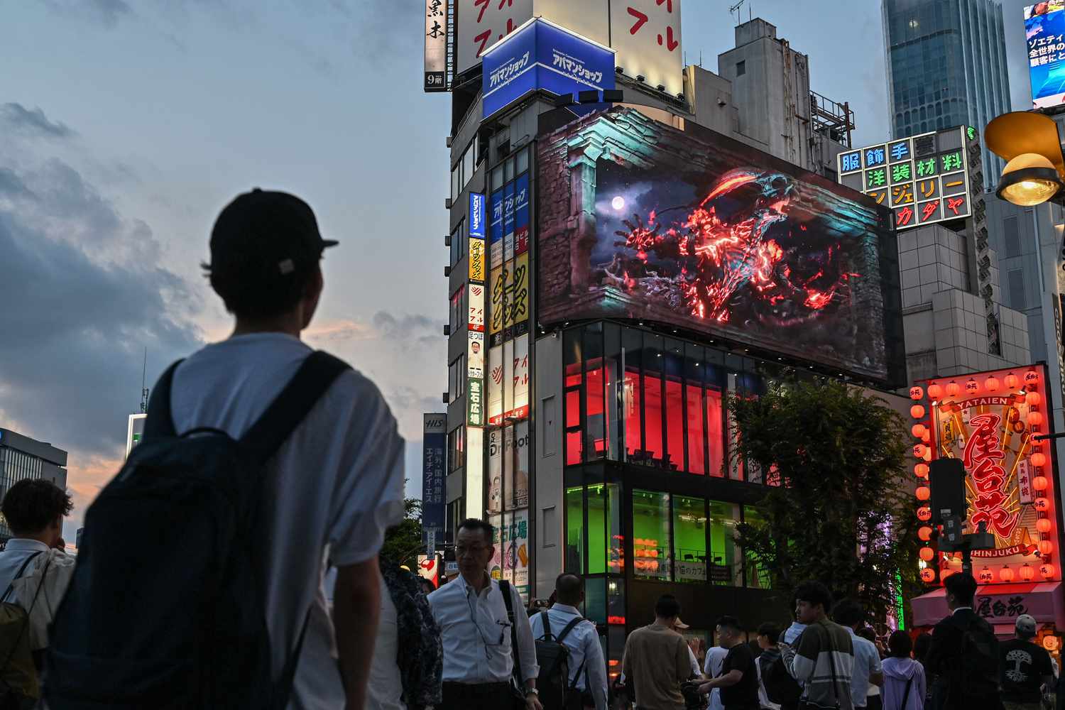 People below a screen promoting a "Final Fantasy" game in Tokyo in 2023. 