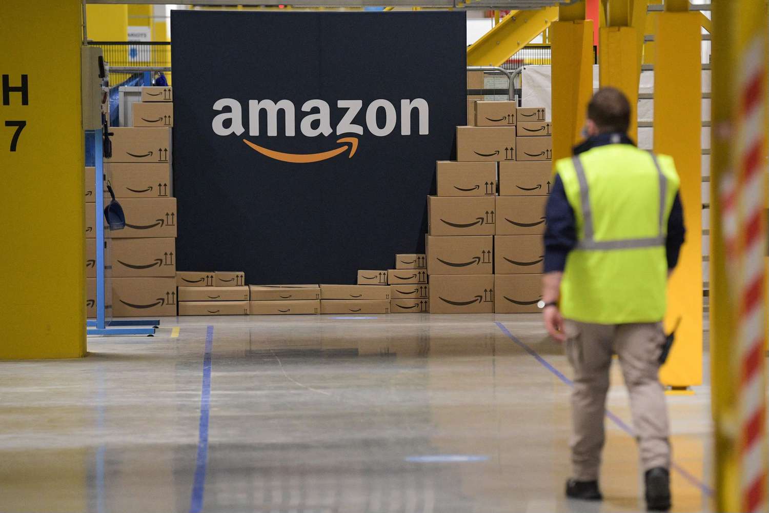 Amazon packages are stacked next to the company's logo.