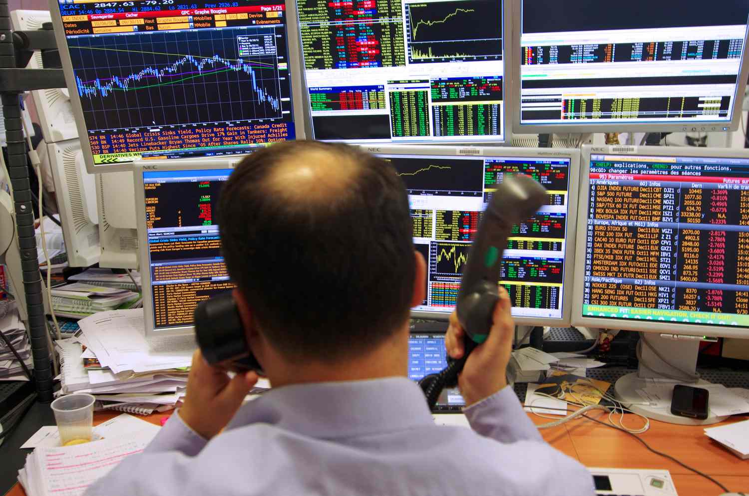 Trader on the phone, sitting in front of a bank of computers