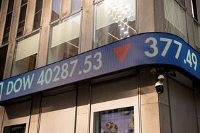 A long screen displays market news, including the Dow price, on the outside of a building.