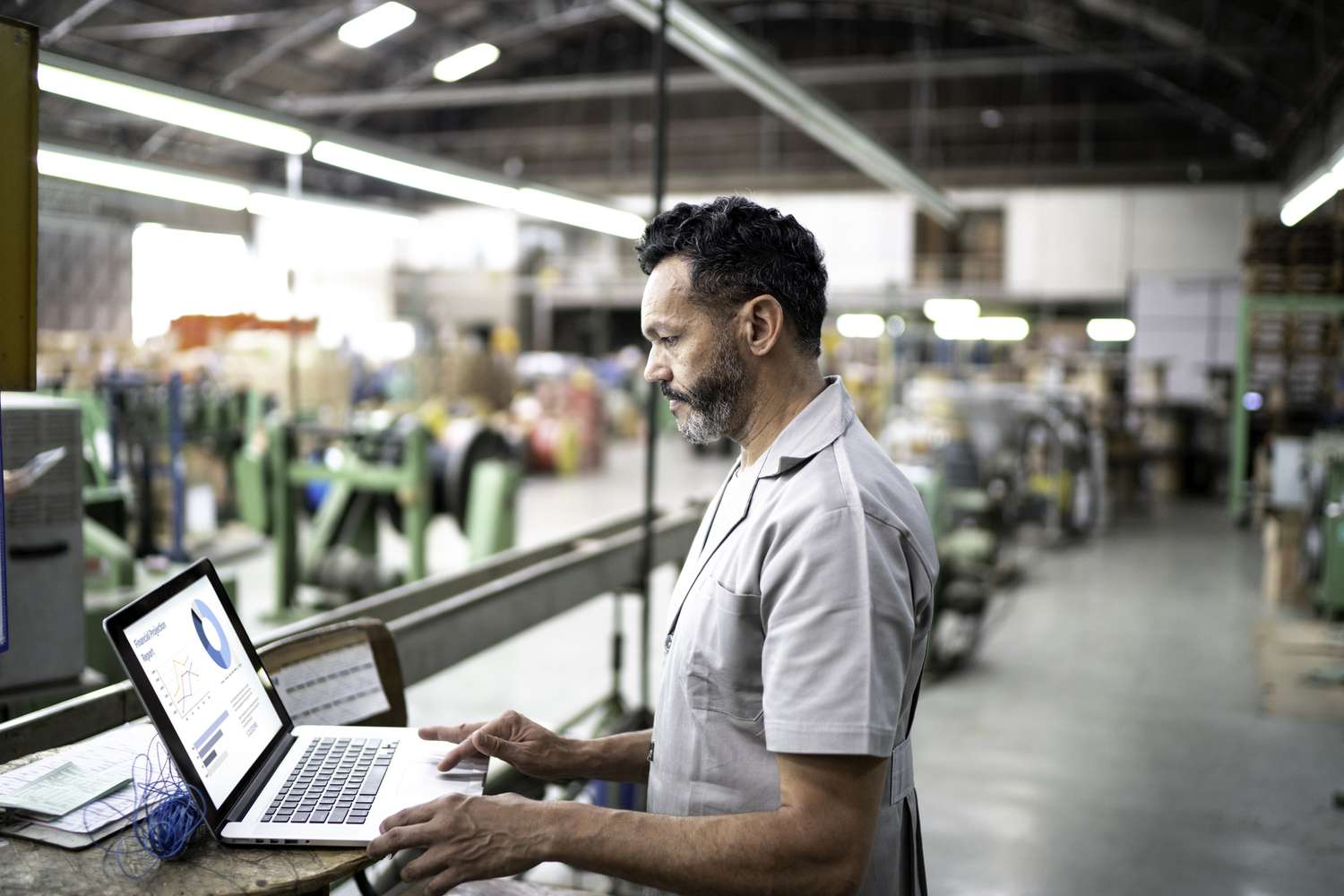  Man using a laptop while working in a factory