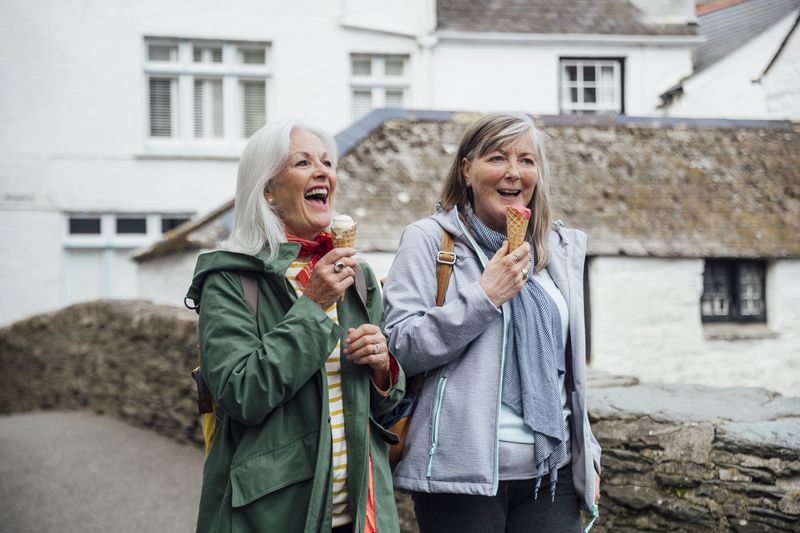 Two friends eat ice cream on a walk.