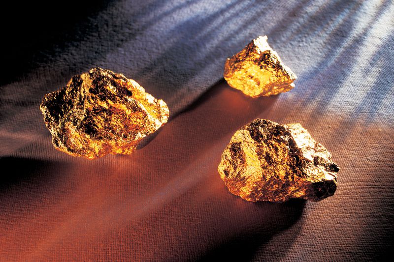 Three large gold nuggets on a table.