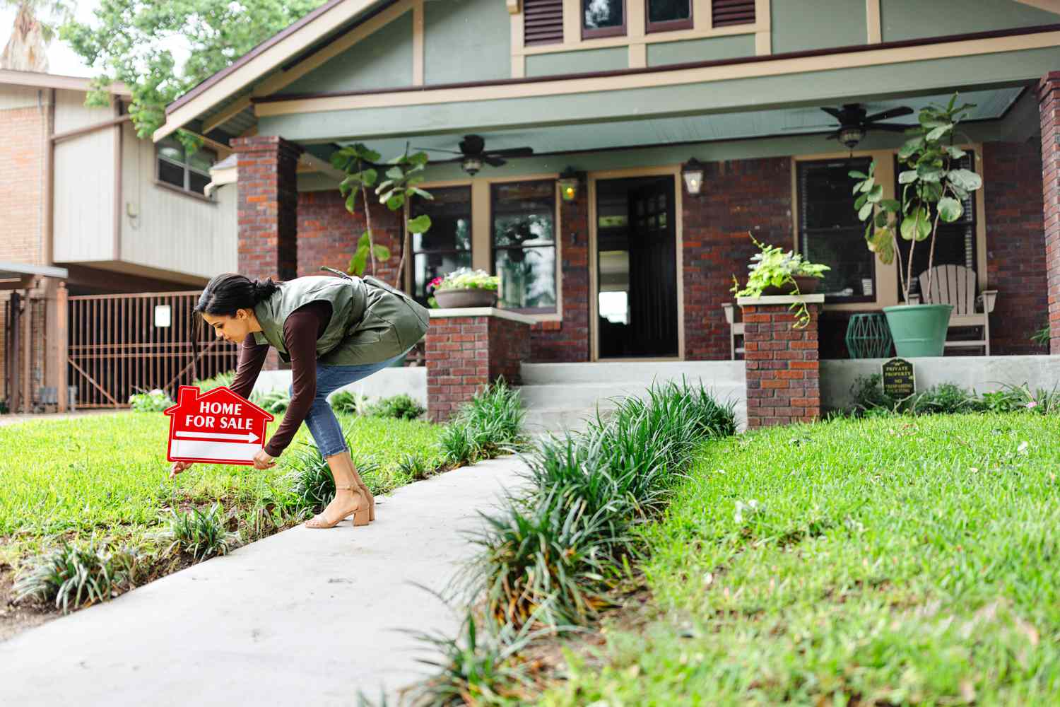 A realtor places a For Sale sign in the front yard of a home preparing it for sale.