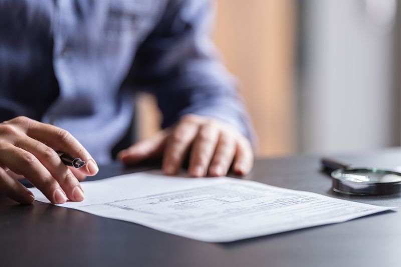 Close up of man sitting at desk with pen in hand about to fill out form