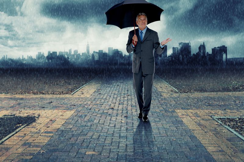 A businessman walking with umbrella during the storm.
