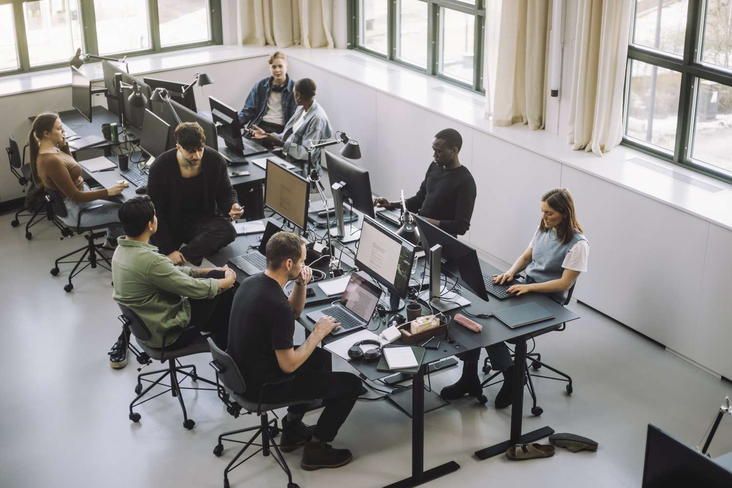 Workers sit at desks in an open concept office. 